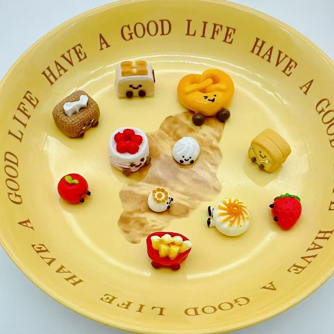 Angled view of 11 JellyCat-themed Taba Squishies displayed on a yellow plate, including apple, fries, and mini buns.