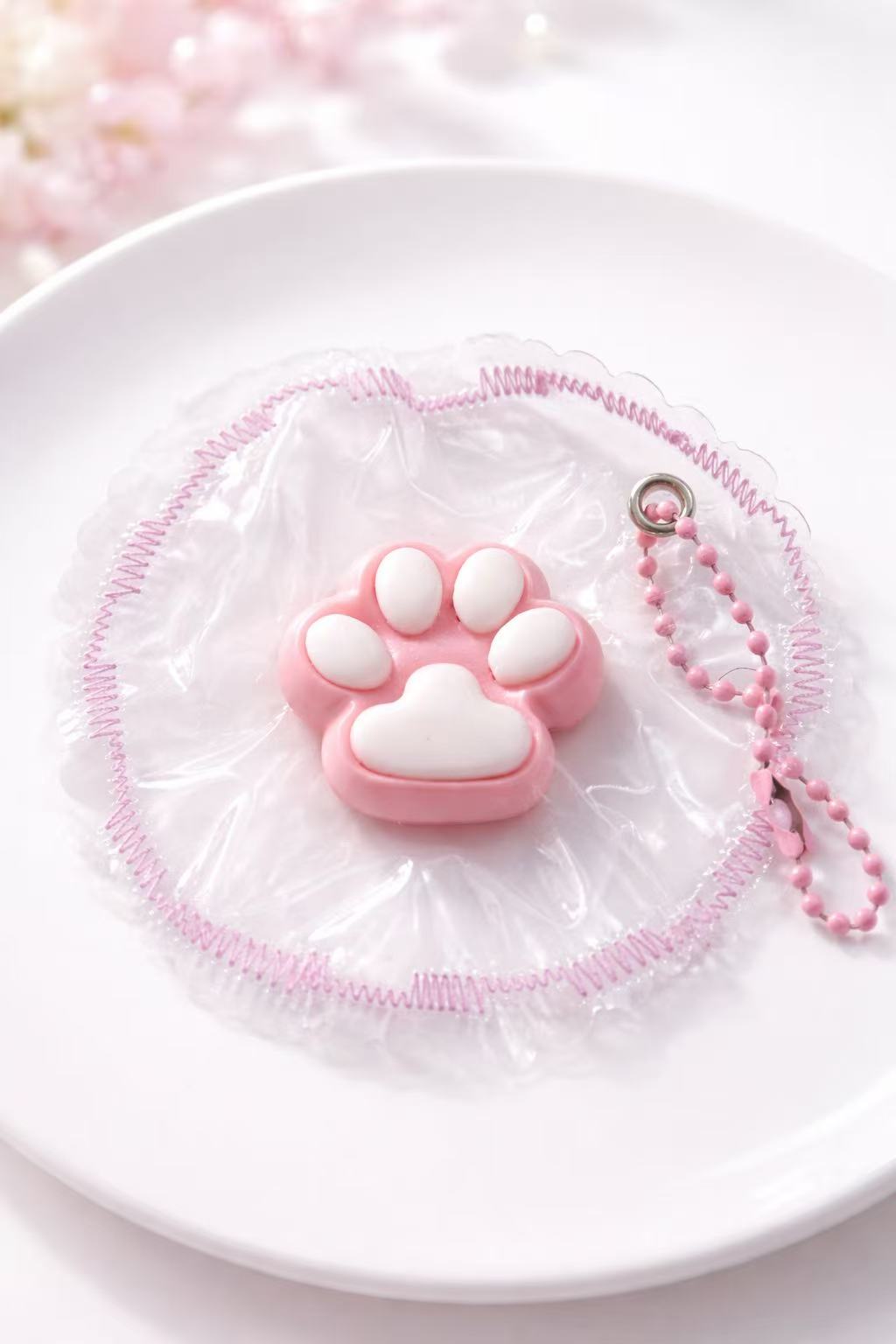 Pink paw-shaped taba squishy on a white plate with a soft pink background