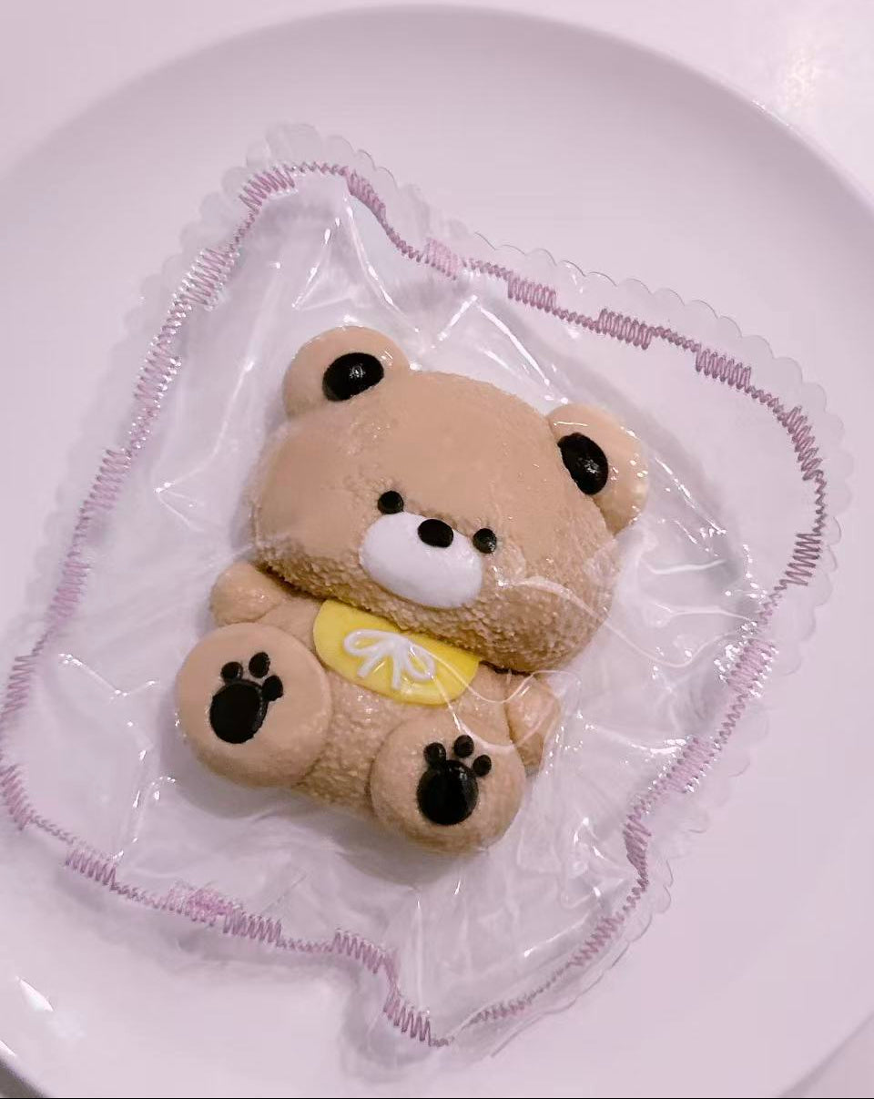 Side view of cute bear taba squishy with chubby teddy bear details, handmade silicone stress relief toy in decorative packaging