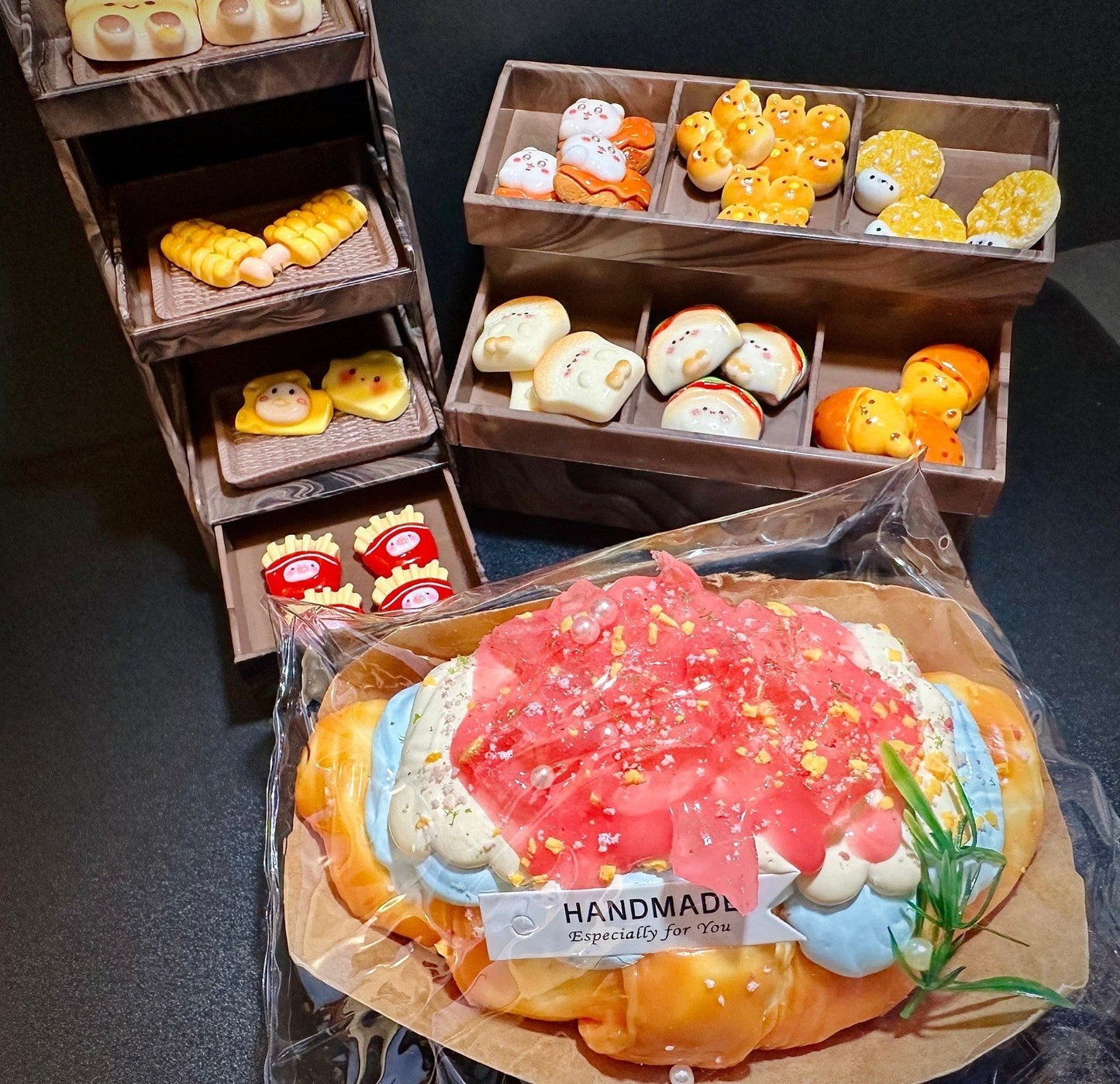 Handmade dreamy peach croissant squishy displayed with miniature bakery toys in wooden trays