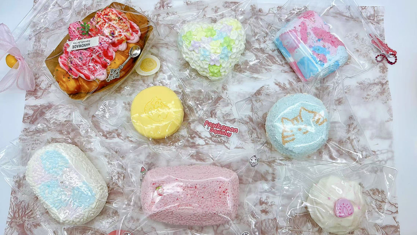 Showcase of colorful handmade regular-size Taba squishies, featuring heart shapes, cream buns, and decorative textures, each sealed in clear packaging with visible labels.