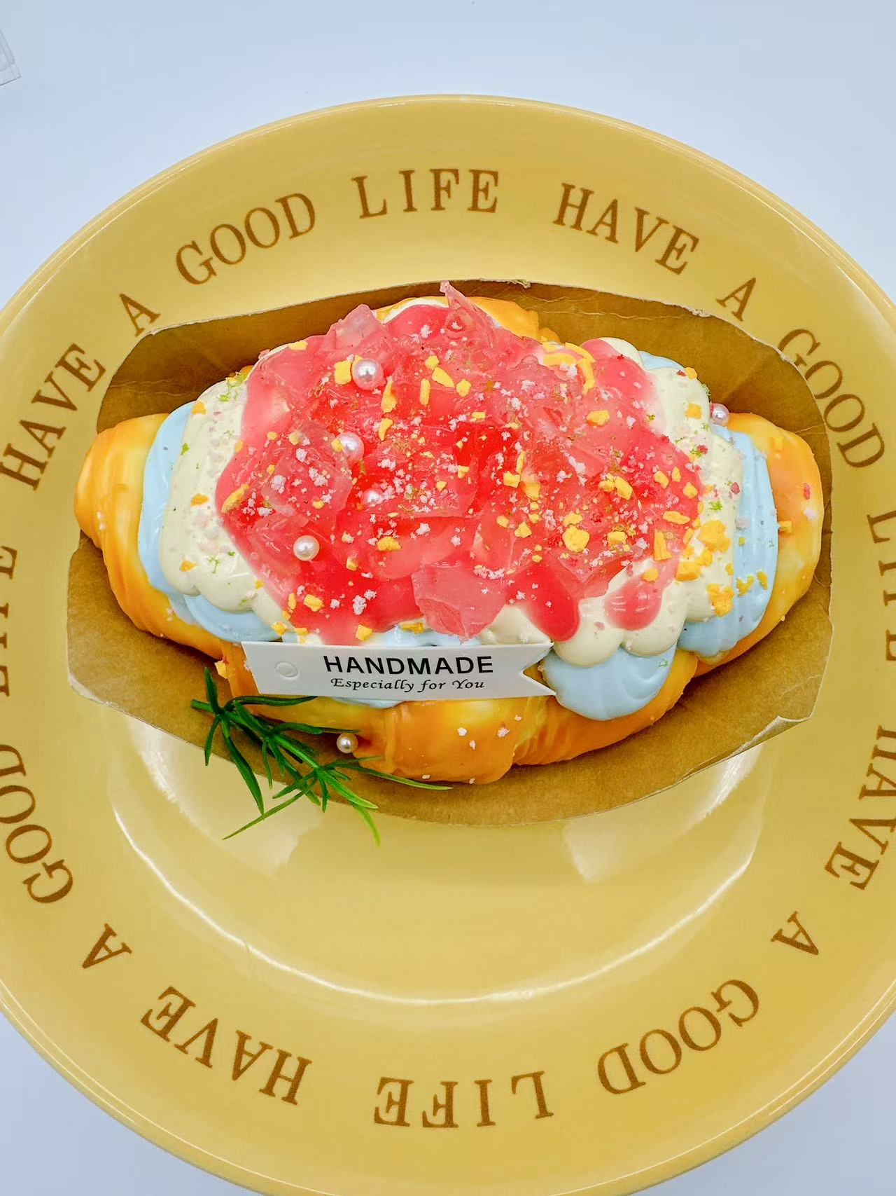 peach croissant squishy in a tray displayed in a yellow plate