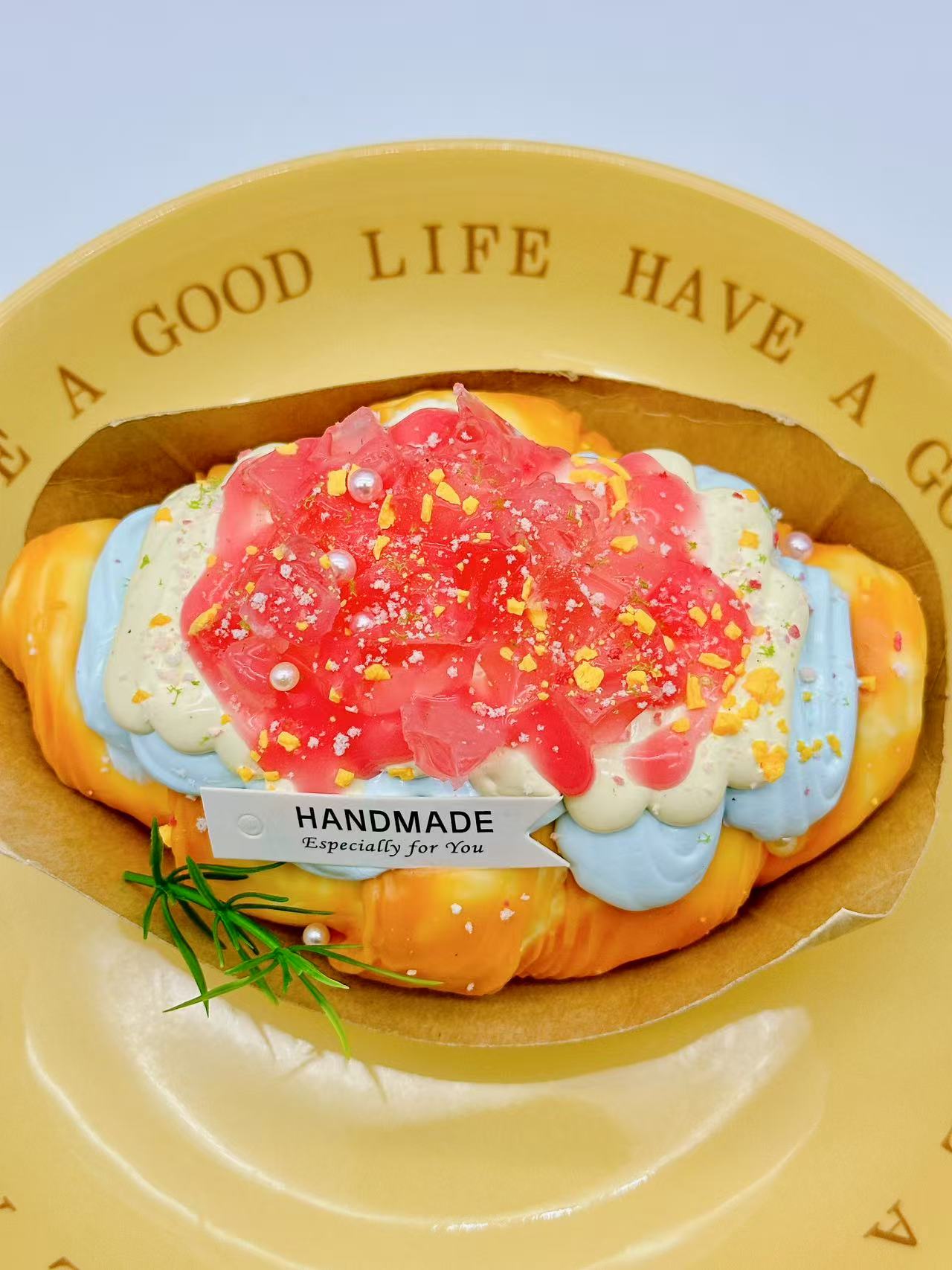 Peach croissant squishy with pink topping and cream layers on a yellow plate with text.