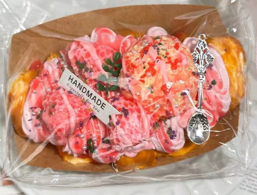 Angled close-up of Rosé Royale croissant squishy toy in packaging, highlighting jelly texture and gold flakes