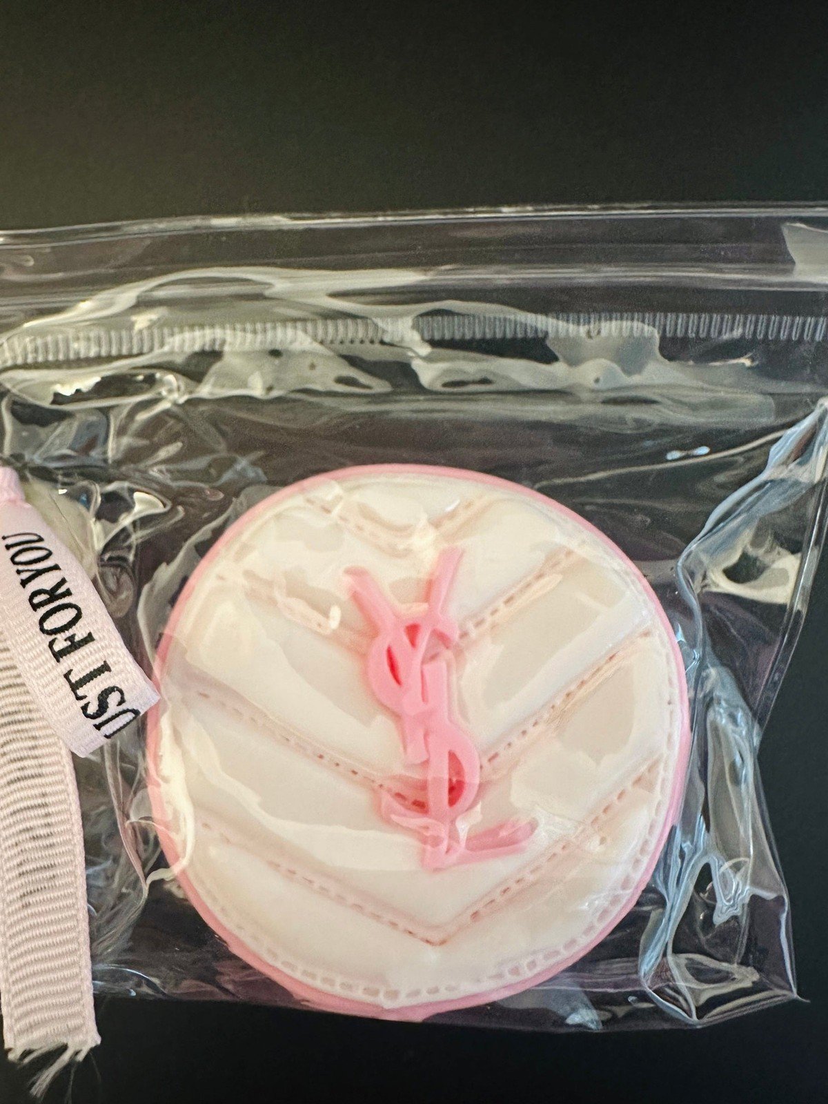 Close-up of YSL cushion-inspired squishy in transparent packaging with pink logo