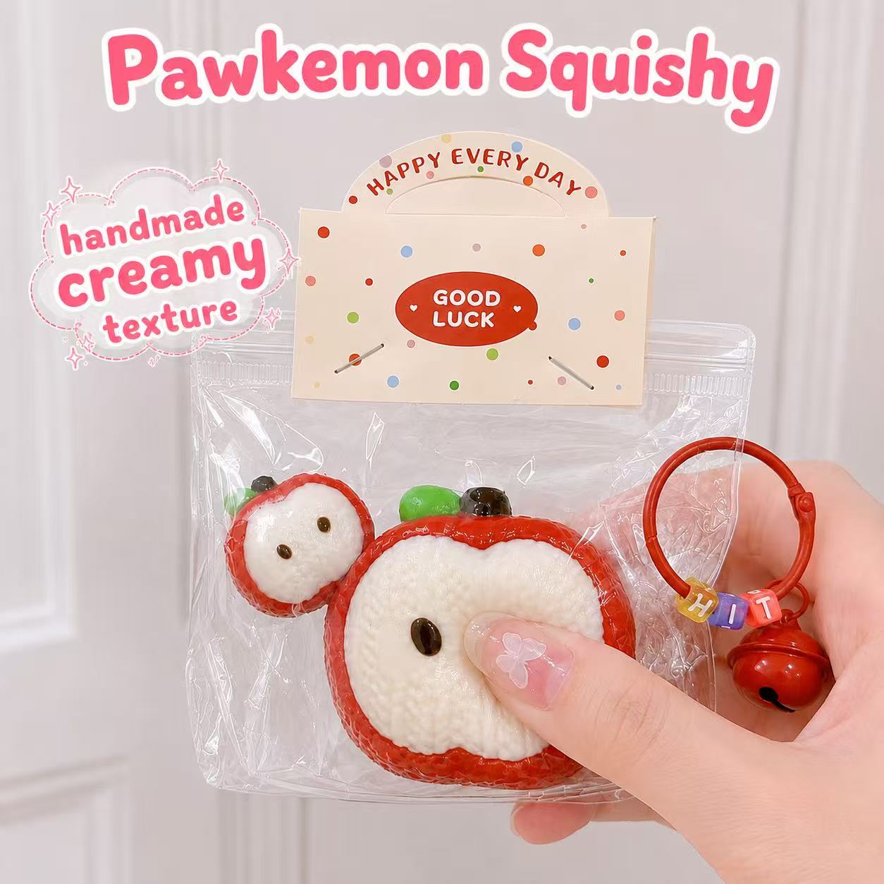 Hand holding the 2pc Knitted Apple Taba Squishy, showing its soft handmade silicone texture, creamy slow-rising feel, apple slice design, clear packaging, and cute red charm.