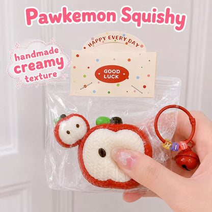 Hand holding the 2pc Knitted Apple Taba Squishy, showing its soft handmade silicone texture, creamy slow-rising feel, apple slice design, clear packaging, and cute red charm.