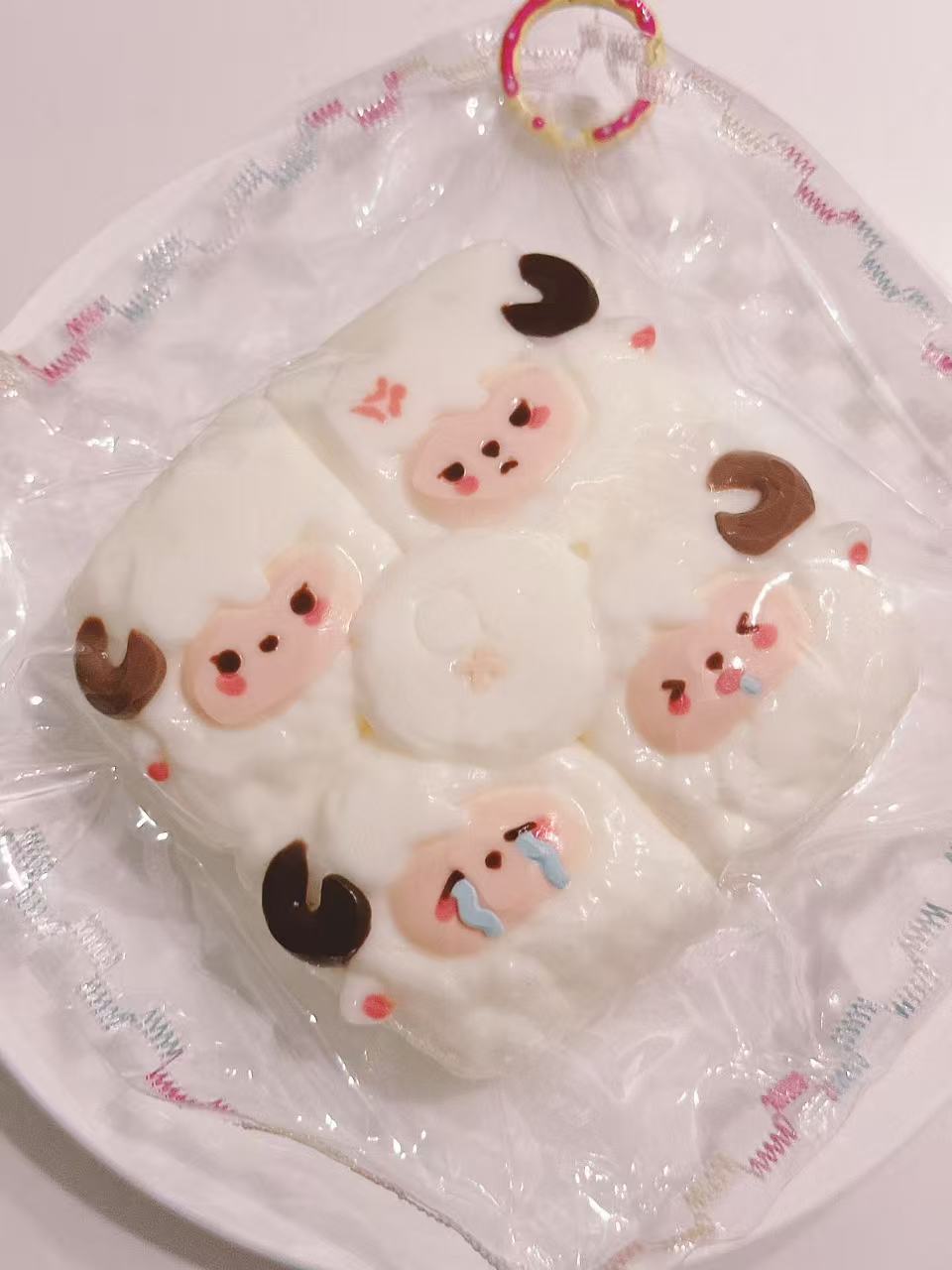 Side view of a handmade 4-in-1 Sheep Taba Squishy showing its rounded shape, four sheep faces, and transparent packaging