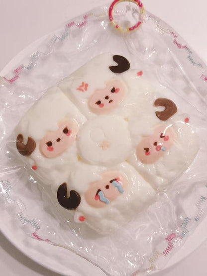 Side view of a handmade 4-in-1 Sheep Taba Squishy showing its rounded shape, four sheep faces, and transparent packaging