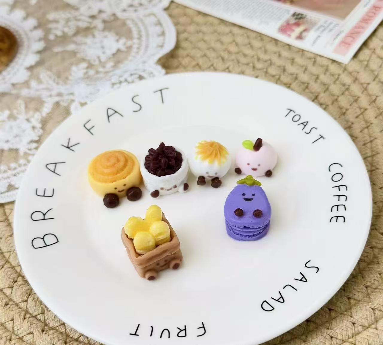 Six mini food-inspired Jellycat Yum Yum squishies with smiling faces arranged on a white plate.