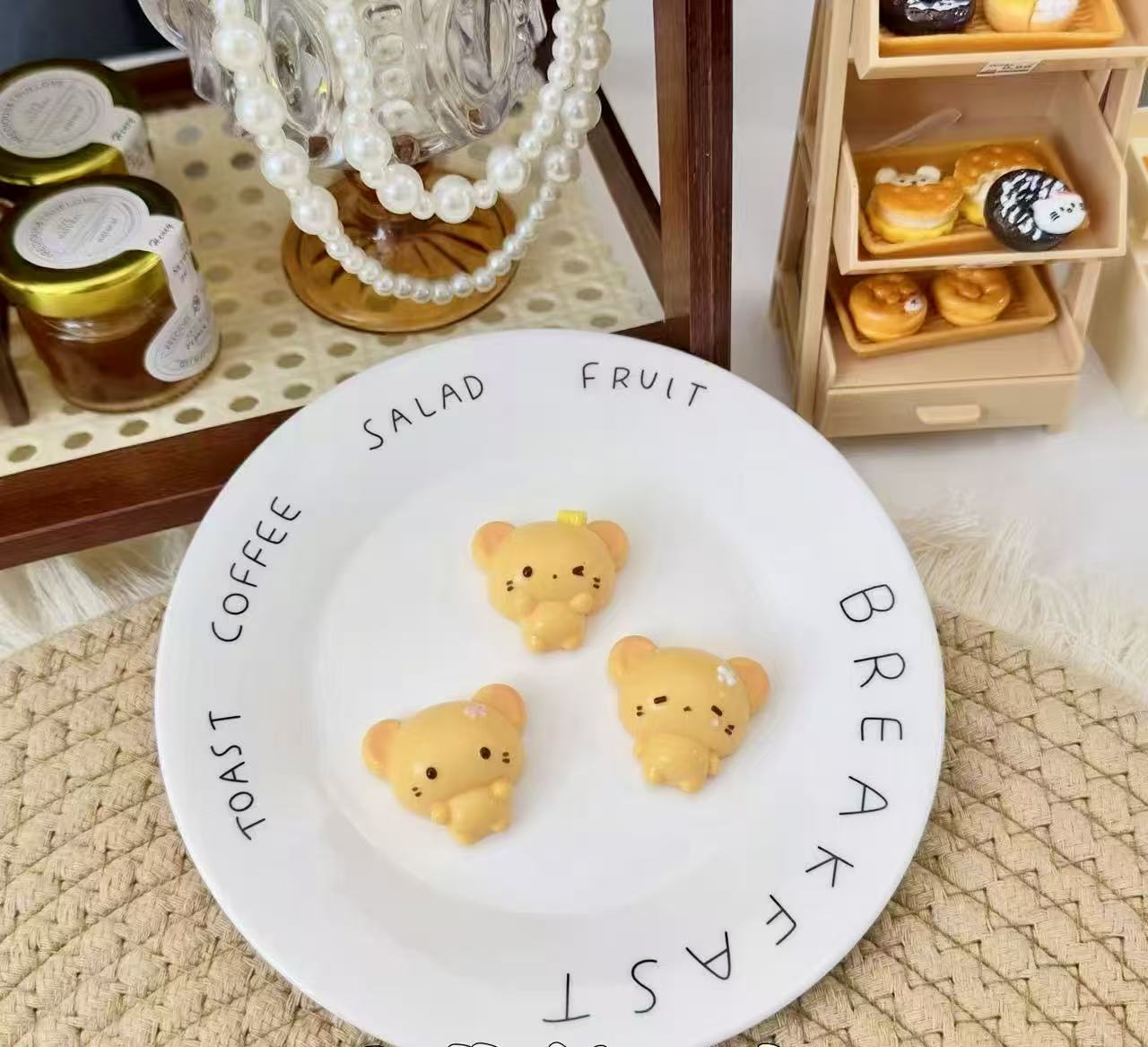Three golden-yellow handmade bear squishies with tiny floral details, displayed on a white plate 