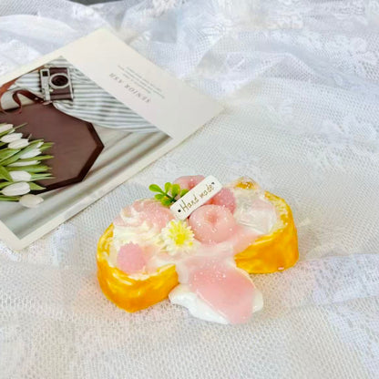 Handmade peach toast squishy topped with pink glaze, peach halves, whipped cream, and daisy flower décor