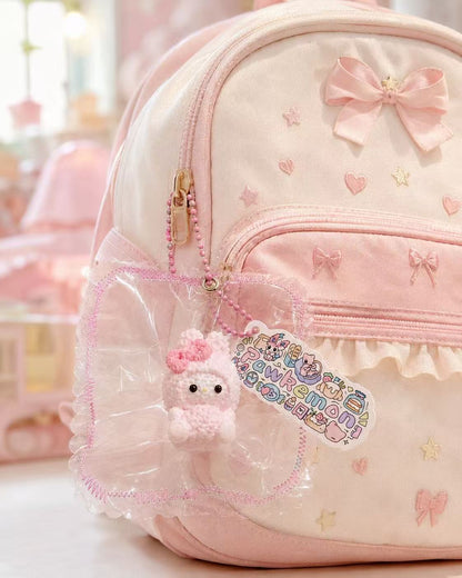 Pink Bunny Taba Squishy hanging as a cute bag charm from a pastel children’s backpack, with clear packaging, pink bead chain, and Pawkemon Squishy tag.
