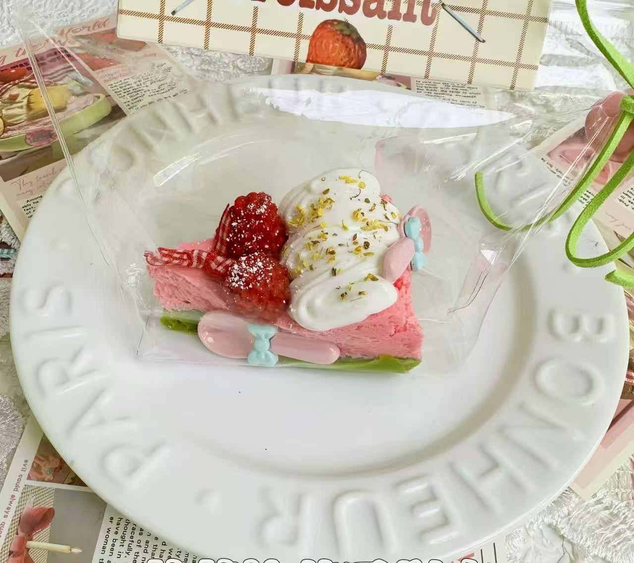 A handmade raspberry chantilly squishy shaped like a cake slice with pink sponge, cream swirls, fresh berries, and golden sprinkles, soft stress relief toy.