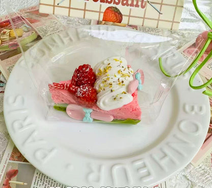 A handmade raspberry chantilly squishy shaped like a cake slice with pink sponge, cream swirls, fresh berries, and golden sprinkles, soft stress relief toy.