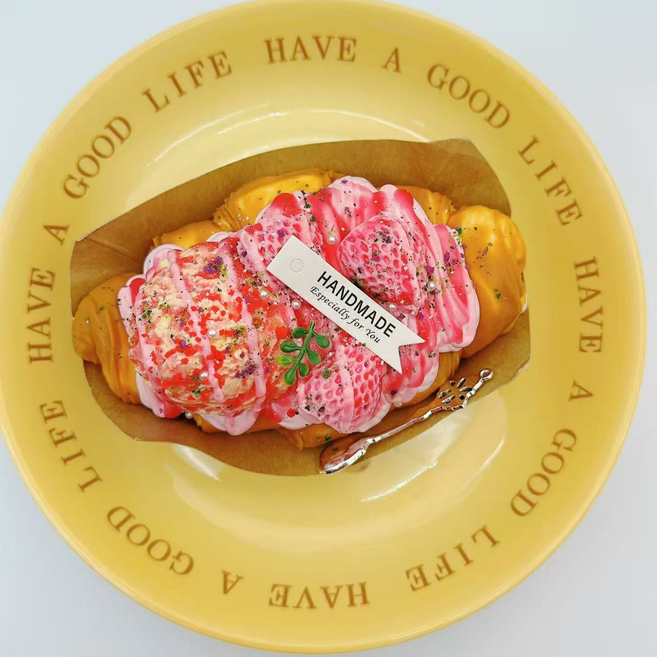 Angled close-up of Rosé Royale croissant squishy toy in packaging, highlighting jelly texture and gold flakes