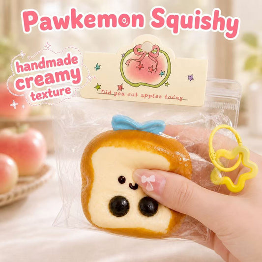 Hand squeezing the Baby Toast Taba Squishy, showing its soft handmade silicone texture, creamy slow-rising feel, cute toast face, blue bow detail, and clear display packaging.