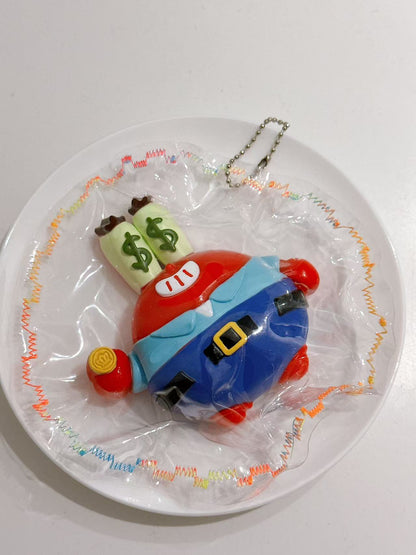 Left-side view of a handmade Cartoon Crab Taba Squishy showing its 3D shape, blue outfit, and transparent packaging