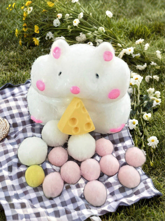 Adorable cheese stealing hamster squishy displayed outdoors on a picnic cloth with pastel decorative balls, perfect for kawaii collection.