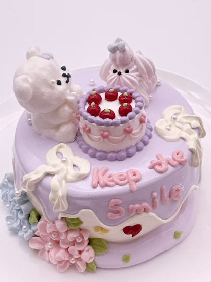 Side view of a handmade Double Puppy Cake Taba Squishy showing the layered cake, frosting details, flowers, and puppy figures
