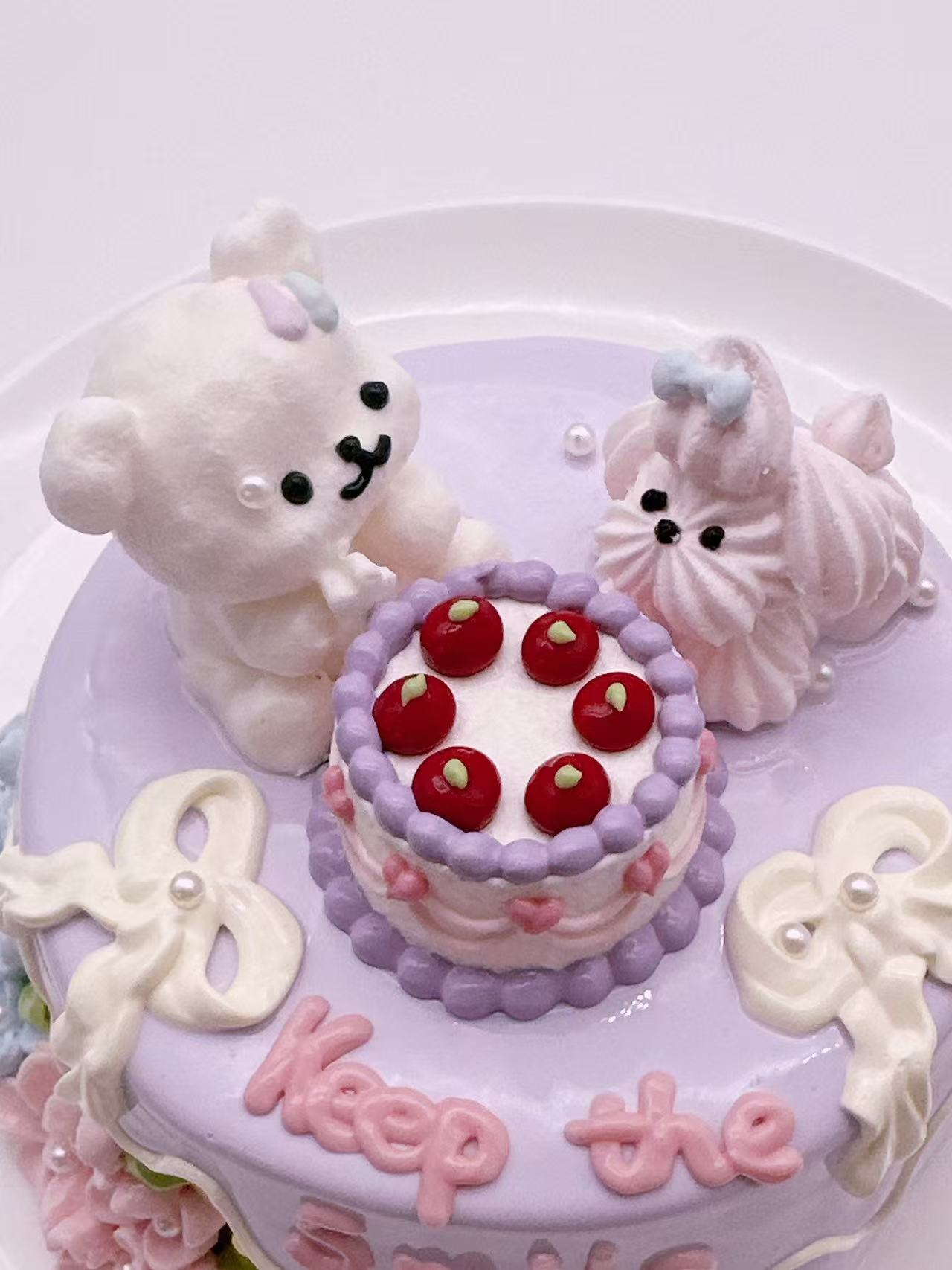 Top view of a handmade Double Puppy Cake Taba Squishy with two puppy figures, red berry toppings, and decorative frosting