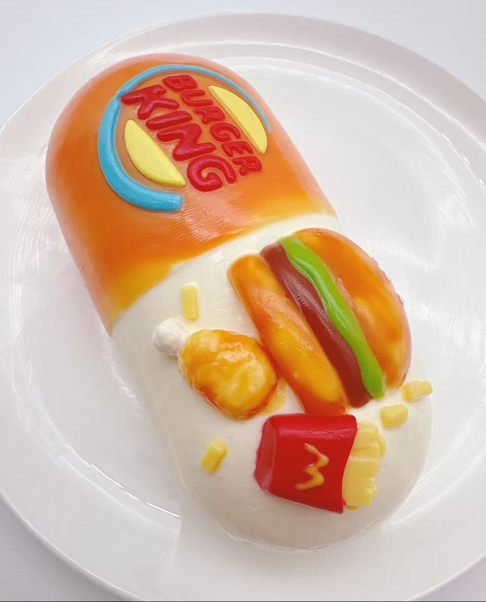 Angled view of fast food burger capsule taba squishy highlighting detailed burger, fries and capsule design in handmade silicone
