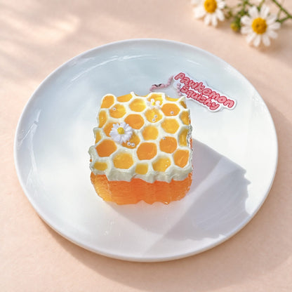 Overhead view of the honeycomb cake Taba Squishy on a white plate, showing its golden honeycomb top.