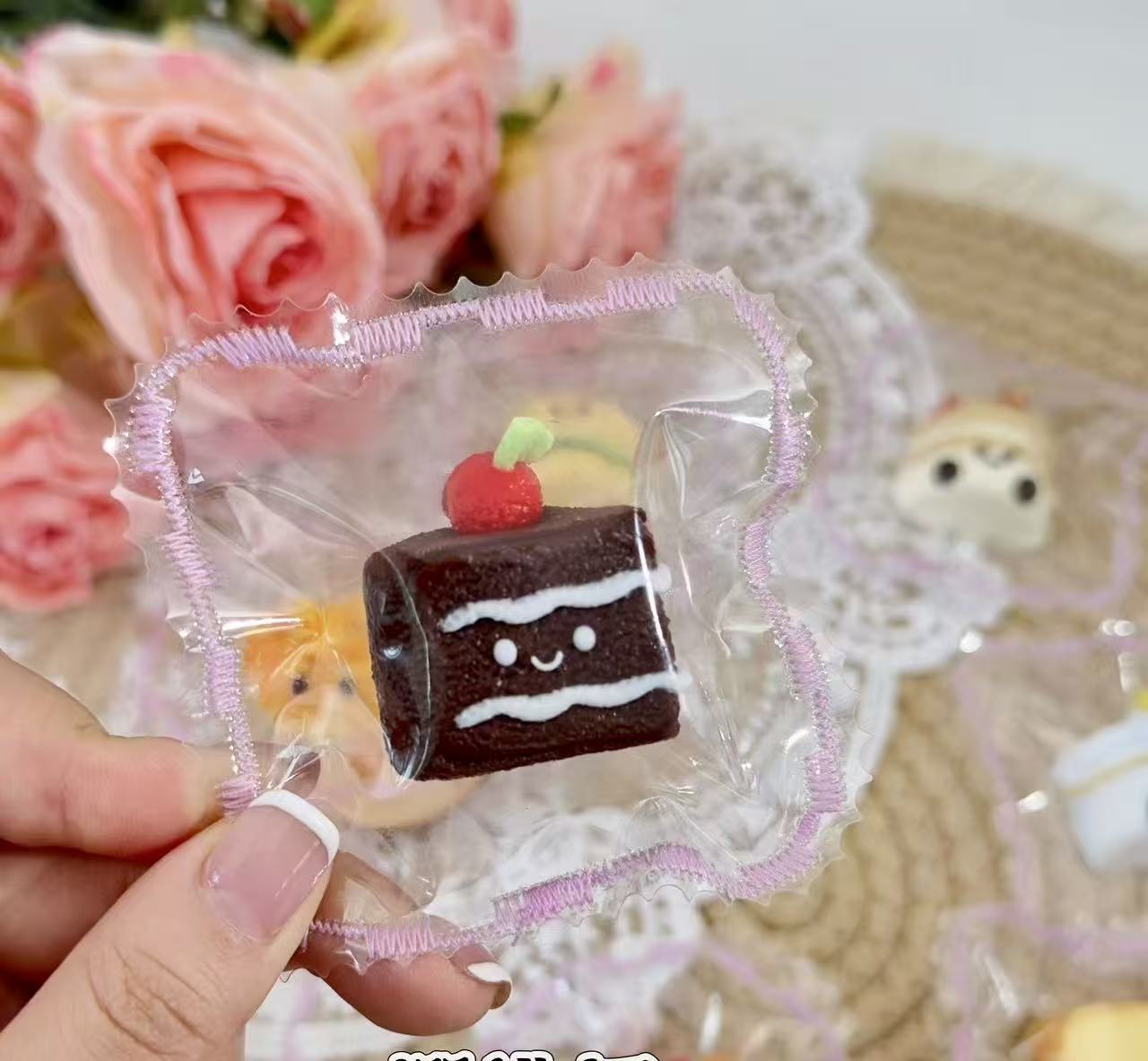 Mini chocolate cherry cake jellycat inspired squishy held in hand, cute kawaii dessert design.
