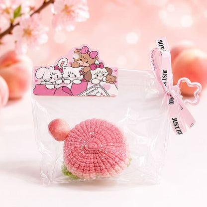 Front view of the Knitted Peach Taba Squishy by Pawkemon Squishy, a handmade silicone peach squishy with a cozy knitted-style texture, pink color, green leaf detail, and clear display packaging.