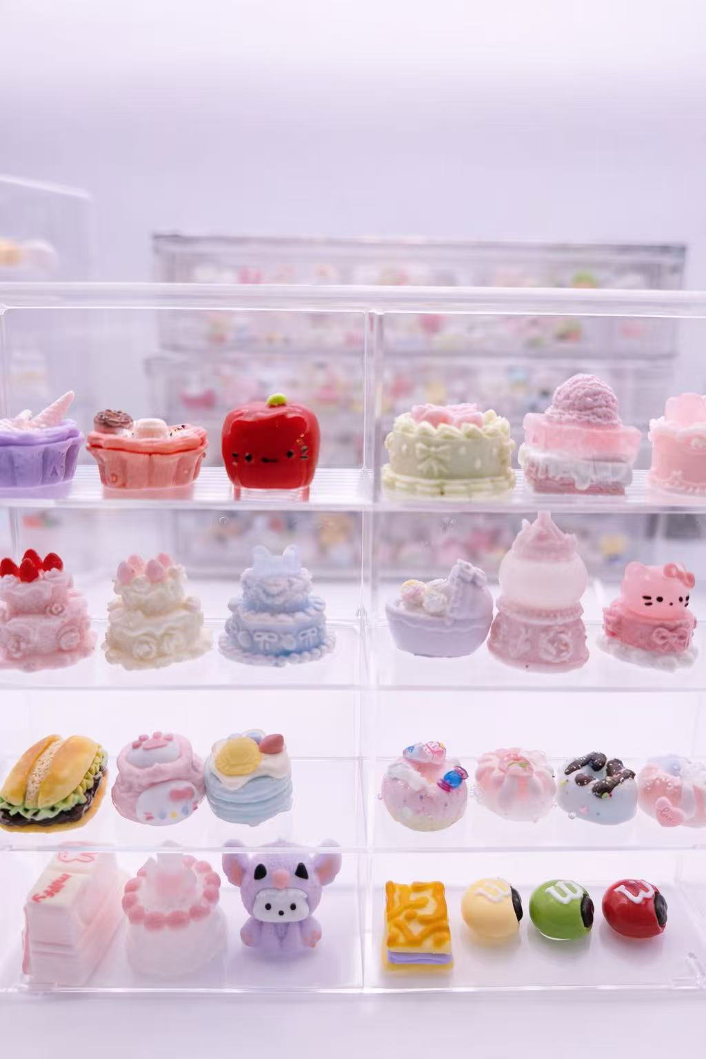 Handmade Luxe Mini Taba Squishy dessert designs displayed on a clear tiered stand, featuring pastel cakes and sweets