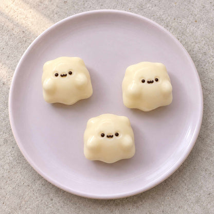 Three creamy white mini ghost Taba Squishies arranged on a pale lavender plate in soft natural light.