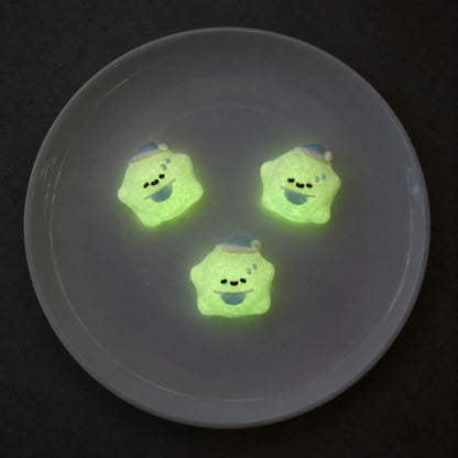 Three mini star Taba Squishies glowing soft green on a dark gray plate in a triangular arrangement.