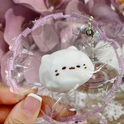 Handheld Mochi Meow Taba Squishy showing the cute white mochi cat face and detailed frilled packaging, handmade by Pawkemon.
