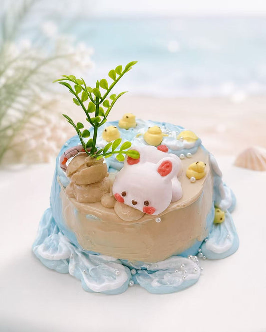 Handmade Bunny Beach Cake Taba Squishy with ocean wave icing, tiny yellow ducks, pearl details, and a sleeping bunny on a pastel beach cake.