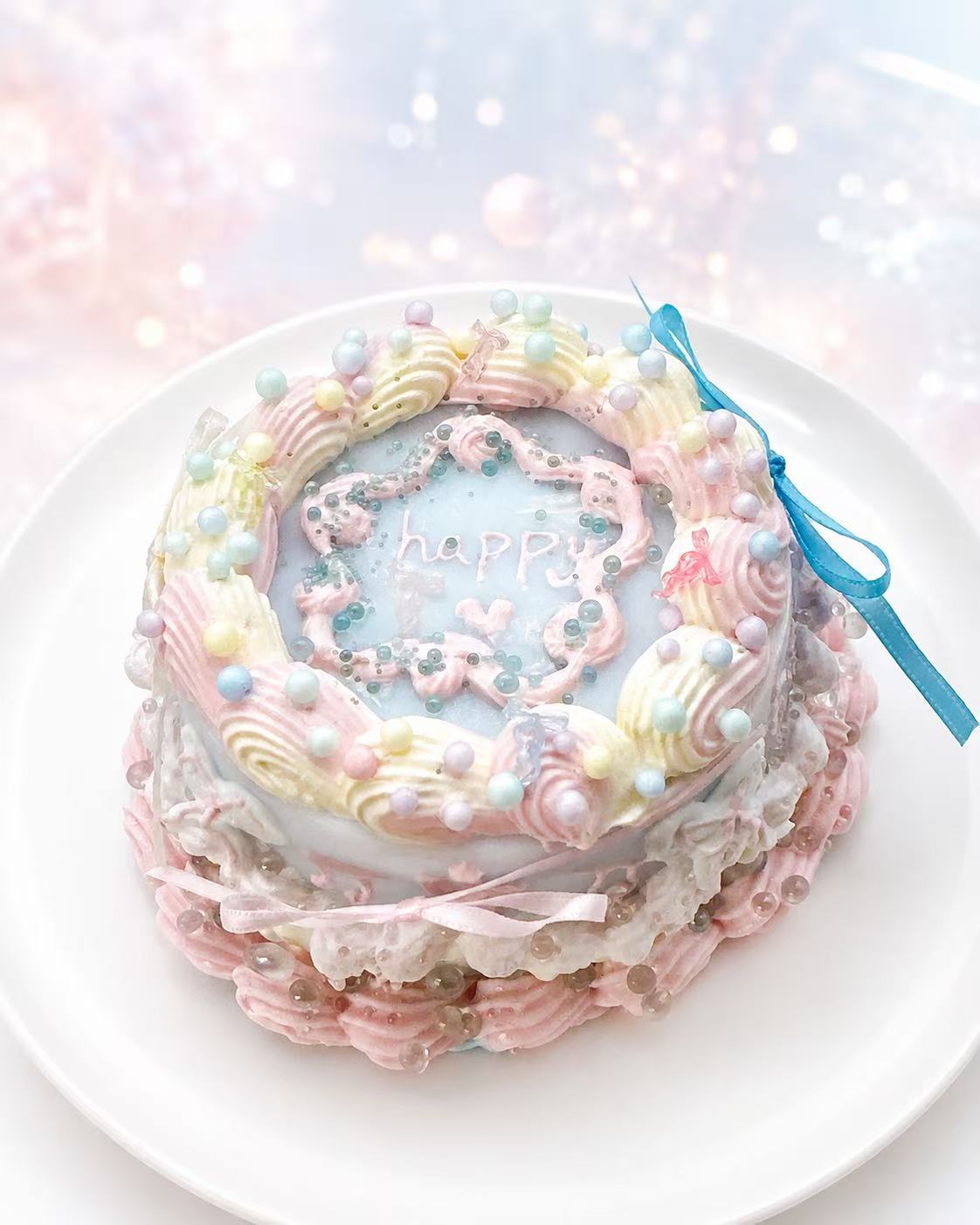 Handmade Ocean Cake Taba Squishy with pastel blue center, “happy” lettering, pink and cream piping, pearl details, and a blue ribbon accent.