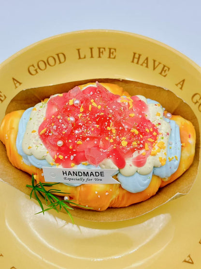 Peach croissant squishy with pink topping and cream layers on a yellow plate with text.