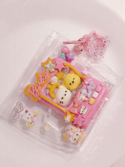 Top view of a handmade pink Claw Machine Taba Squishy showing the transparent packaging, character figures, and decorative details