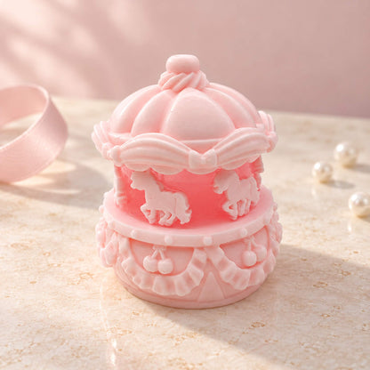 Pink mini carousel Taba Squishy featuring white horses, bows and ornate molded details on a softly lit surface.