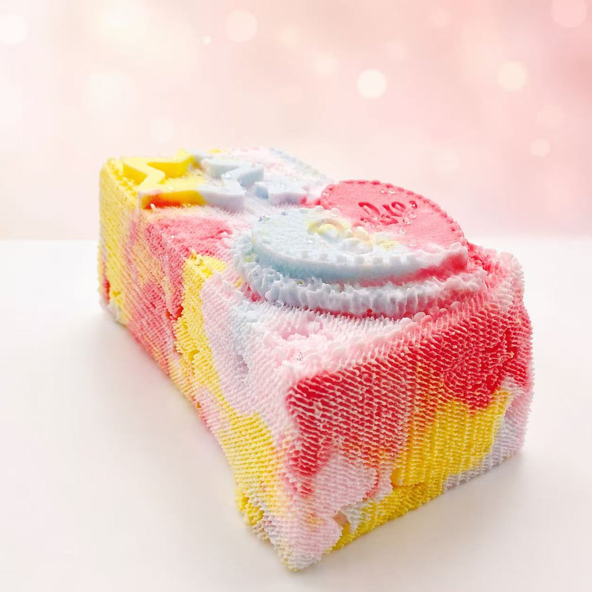 Side view of the Pink Denim Brick Taba Squishy by Pawkemon Squishy, highlighting its soft handmade silicone texture, pastel pink and yellow denim-style pattern, raised heart, star details, and chunky brick shape.