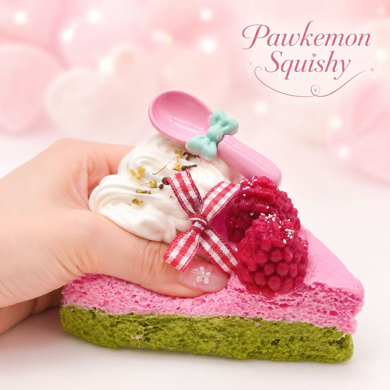 Hand holding the Raspberry Cake Taba Squishy, showing its soft handmade silicone texture, raspberry cake design, whipped cream topping, and collectible dessert shape.
