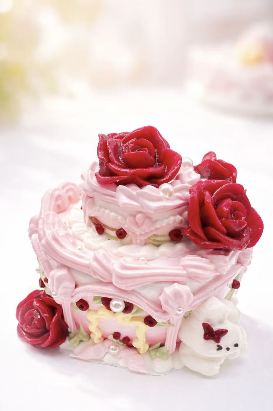 Front view of Rose Palace Bunny Cake Taba Squishy showing red rose decorations, pink cream piping, pearl details, and handmade silicone cake texture.