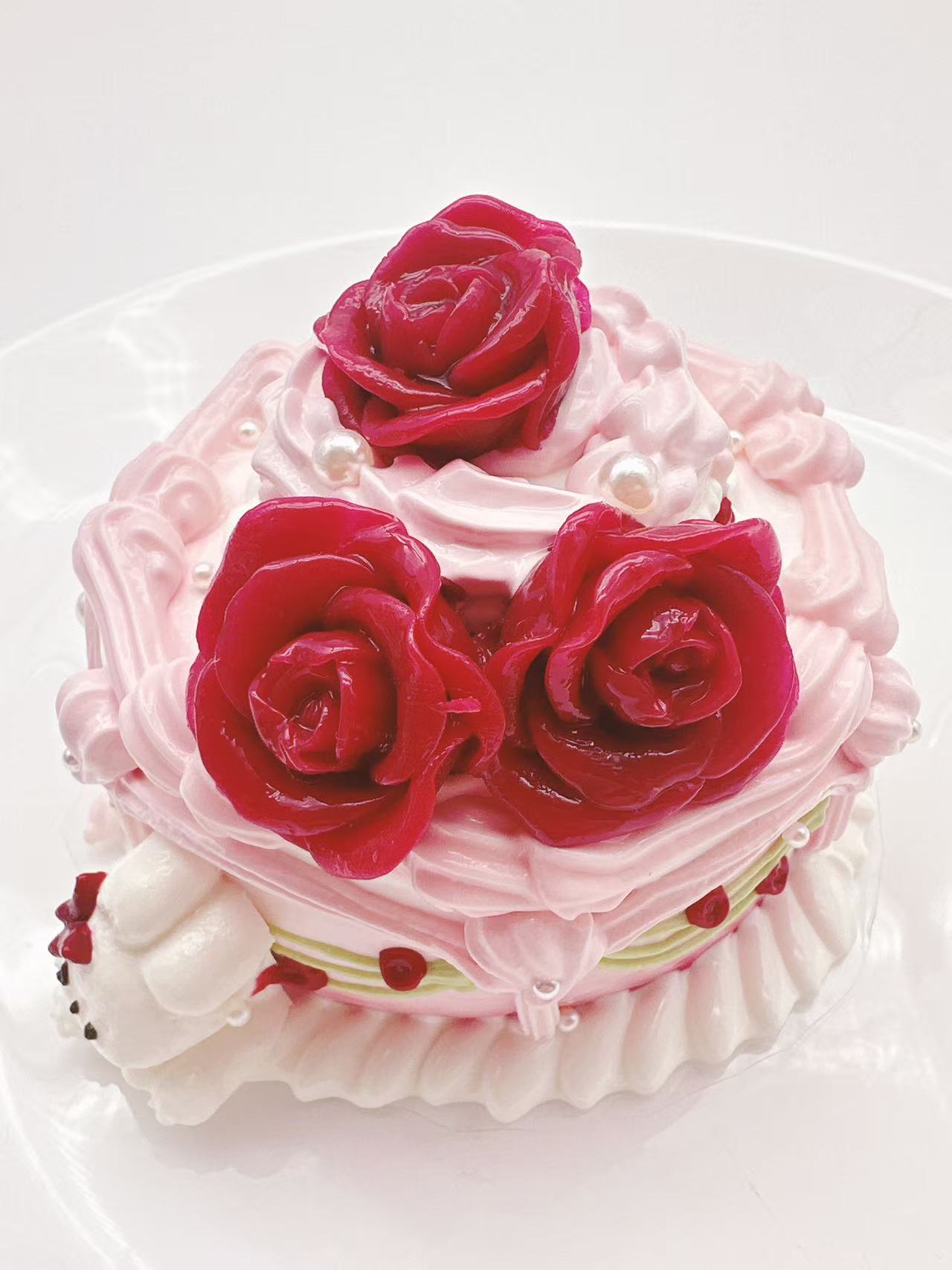 Side view of Rose Palace Bunny Cake Taba Squishy with layered pink cake details, glossy red roses, white bunny charm, and creamy handmade texture.