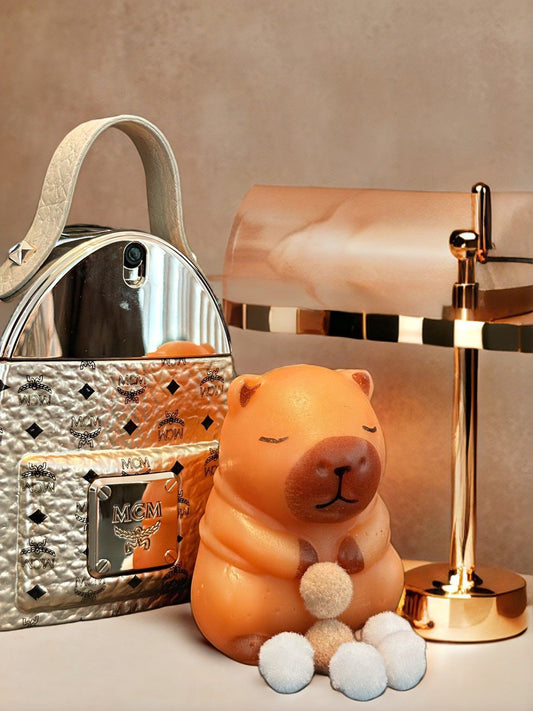 Sage capybara squishy toy displayed on wooden table with accessories, showcasing cute chubby design and soft slow rise texture.