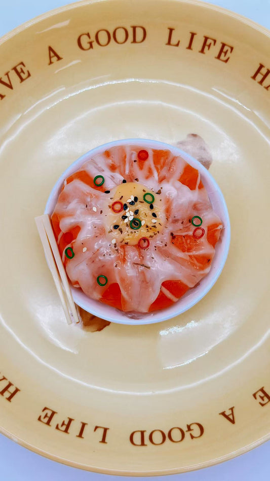 Top-down view of Salmon Don Squishy featuring layered salmon slices, sesame seeds, scallions, and a soft egg yolk center.

