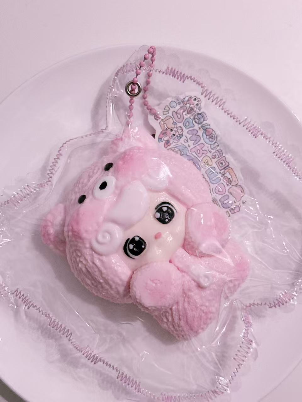 Side view of Sleepy Baby Taba Squishy in pajamas, handmade silicone squishy with gentle sleepy expression and decorative sewn packaging