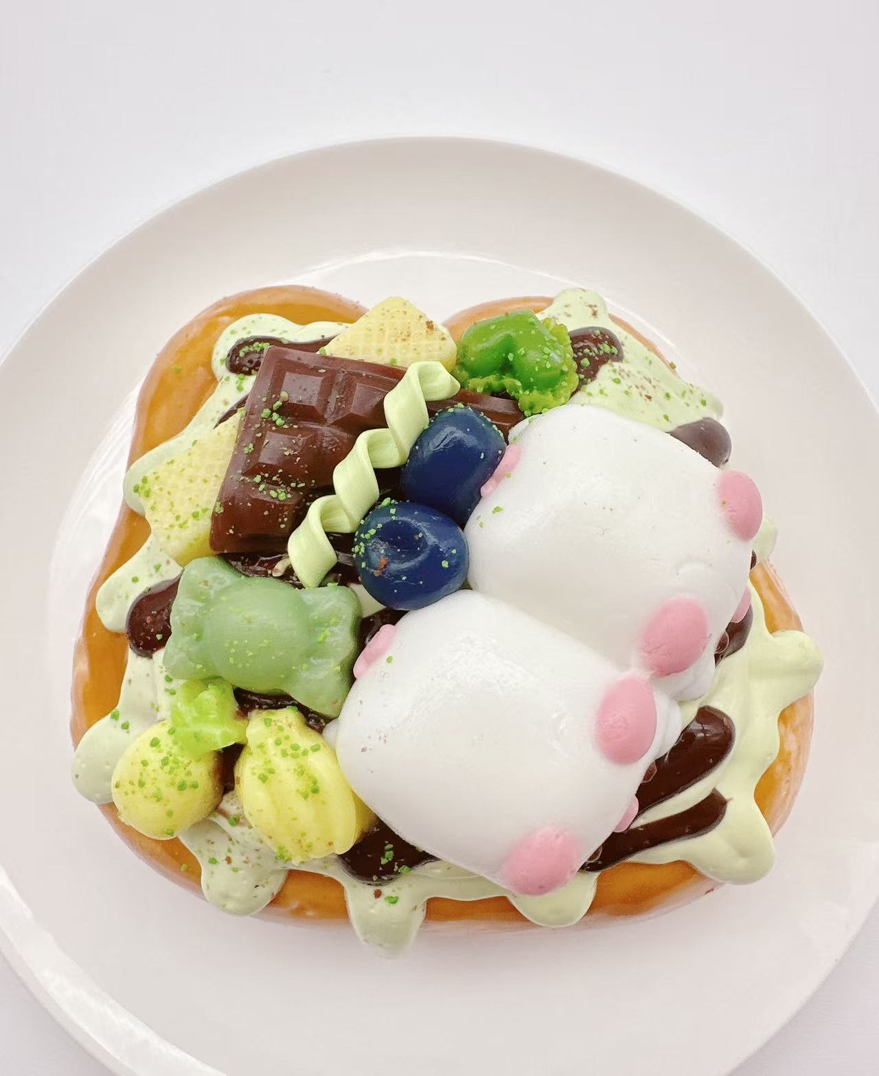 Top view of two pigs dessert toast taba squishy, handmade silicone squishy decorated with candy, fruit, chocolate and cute pig figures
