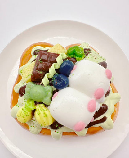 Top view of two pigs dessert toast taba squishy, handmade silicone squishy decorated with candy, fruit, chocolate and cute pig figures
