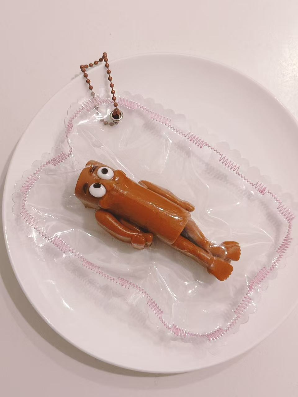 Side view of a handmade Wooden Man Taba Squishy showing its slim 3D character shape and transparent packaging