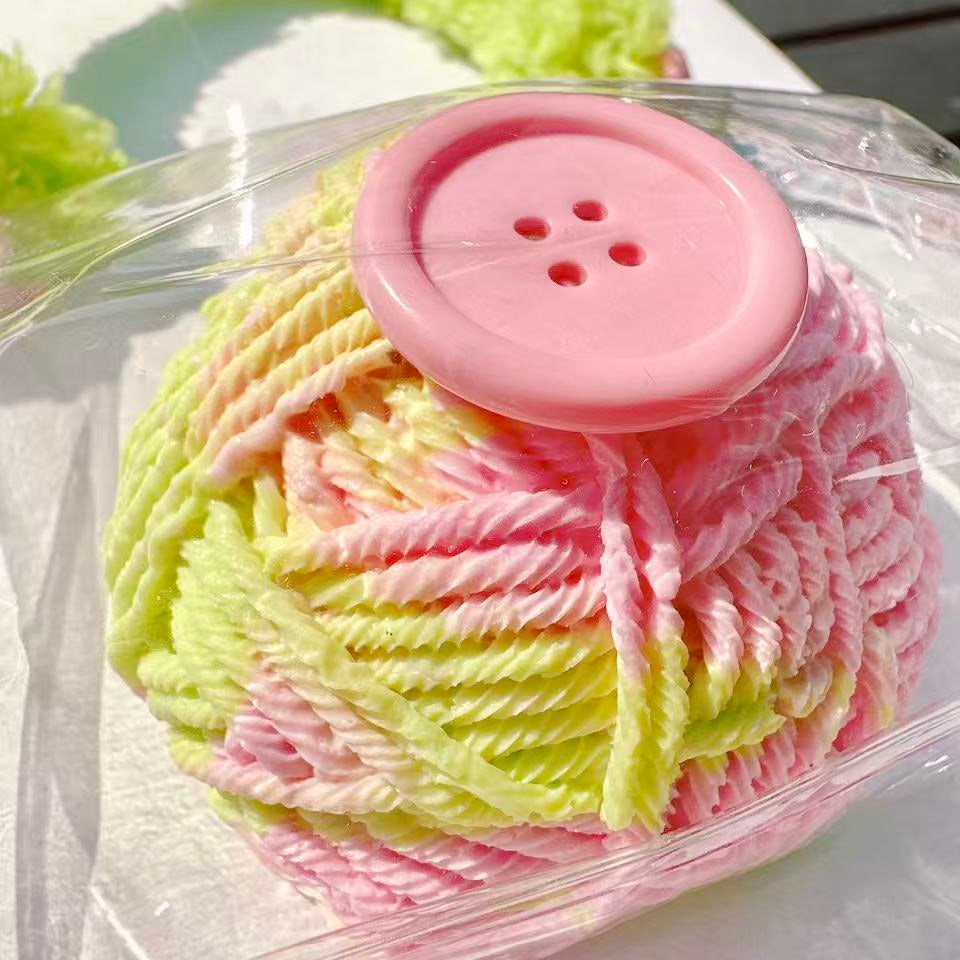 Handmade yarn ball Taba Squishy in pink and green with a cute button design, stress relief toy, kawaii collectible.